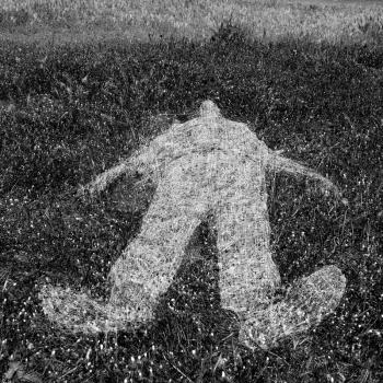 Reclining human figure outline imprinted on grass. Black and white.
