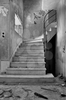 Old staircase and dirty floor in abandoned building interior. Black and white.