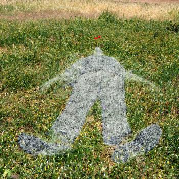 Withered grass ghostlike human figure imprint on green field.