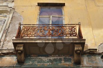 Winged female figure rusty floral pattern and swans on balcony balustrade of abandoned neoclassical house. Athens Greece.