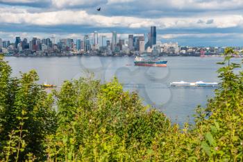 A tugboat pulls a barges in front of the Seattle skyline.