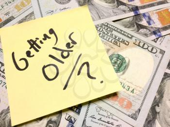 American cash money and yellow post it note with text Getting Older with question mark in black color aerial view