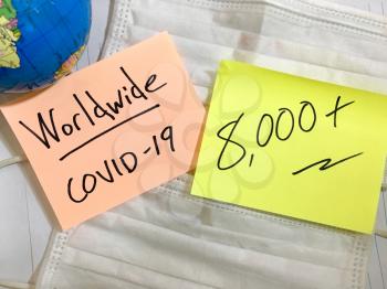 Coronavirus COVID-19 Worldwide infection medical cases and deaths. China COVID respiratory disease influenza virus statistics hand written on surgical mask and earth globe background