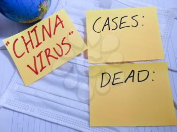 China virus Coronavirus COVID-19 infection medical cases and deaths. COVID respiratory disease influenza statistics hand written on surgical mask and earth globe background