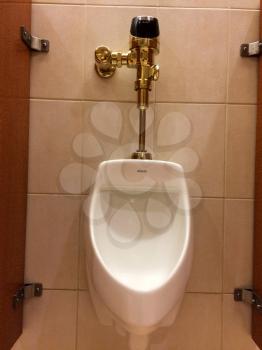 Urinal in mens public restroom bathroom with luxury gold plumbing valve handle