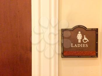 women restroom handicapped public bathroom sign wheelchair pictogram female figure on wood