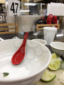 Empty white bowl after finished meal with red spoon at restaurant