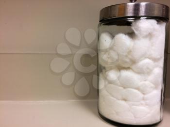 white cotton balls in glass jar on counter of doctors office exam room with text space
