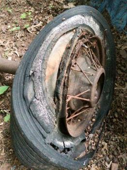 rusty antique ford car parts in backyard with spoked wheels junkyard