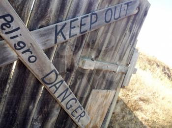 Danger keep out peligro sign painted on wood fence rustic