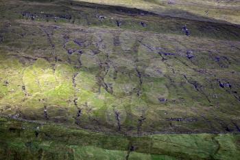 Green grass pattern of pyramid mountains lit with sun beam, Faroe Islands