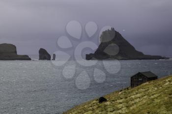 Tindholmur and Drangarnir with dramatic stormy sky as background, Faroe Islands