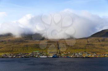 A fluffy cloud hangs over a village in the Faroe Islands