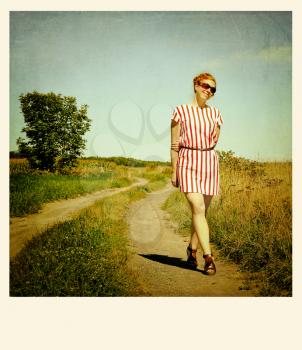 Red hair woman standing in a path.  Cross processed to look like and aged instant picture