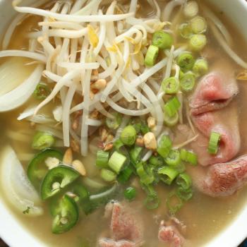 Asian noodle soup with beef, shives, onion, bean sprout and lime