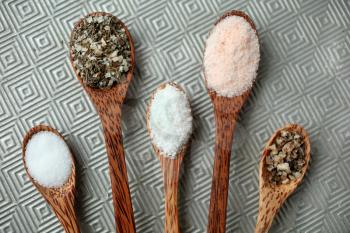 five different kind of salt in a wooden spoon on textured background