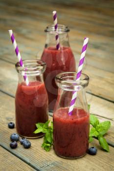 Three blueberry smoothies freshly made in a jar with a lined straw

