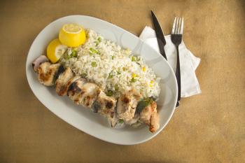 Chicken slouvaki with white rice with peas served with fresh lemon