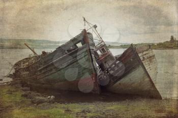 Two old wooden boats aground on isle of Mull, Scotland.  Cross processed to look like an instant picture with texture.