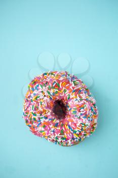 Donut with pink icing and candies on a blue pastel background