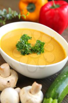 Vegetables soup with fresh mushrooms, zucchini and capsicum on a wooden background
