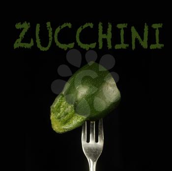 Zucchini piece on a fork on a black background